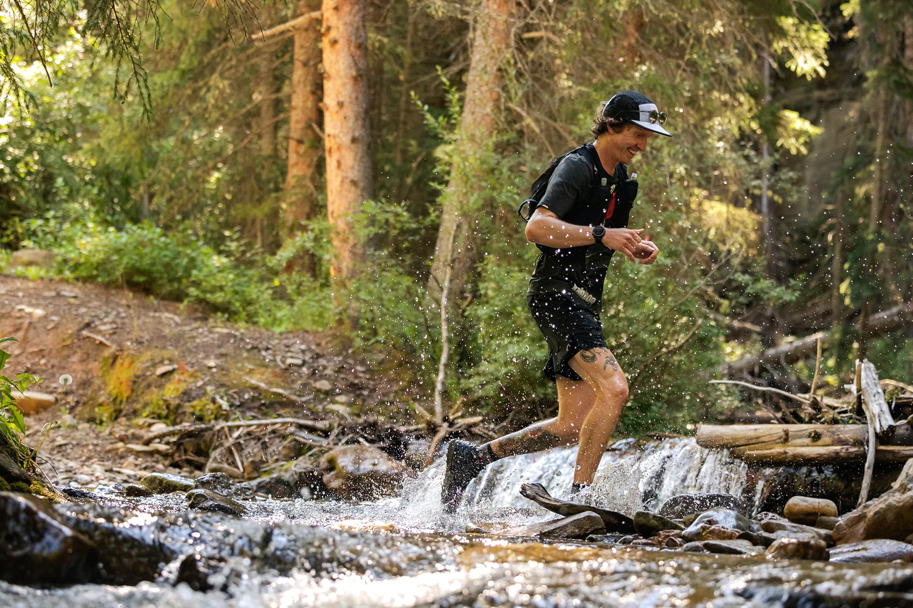 trail runner running through creek in forest